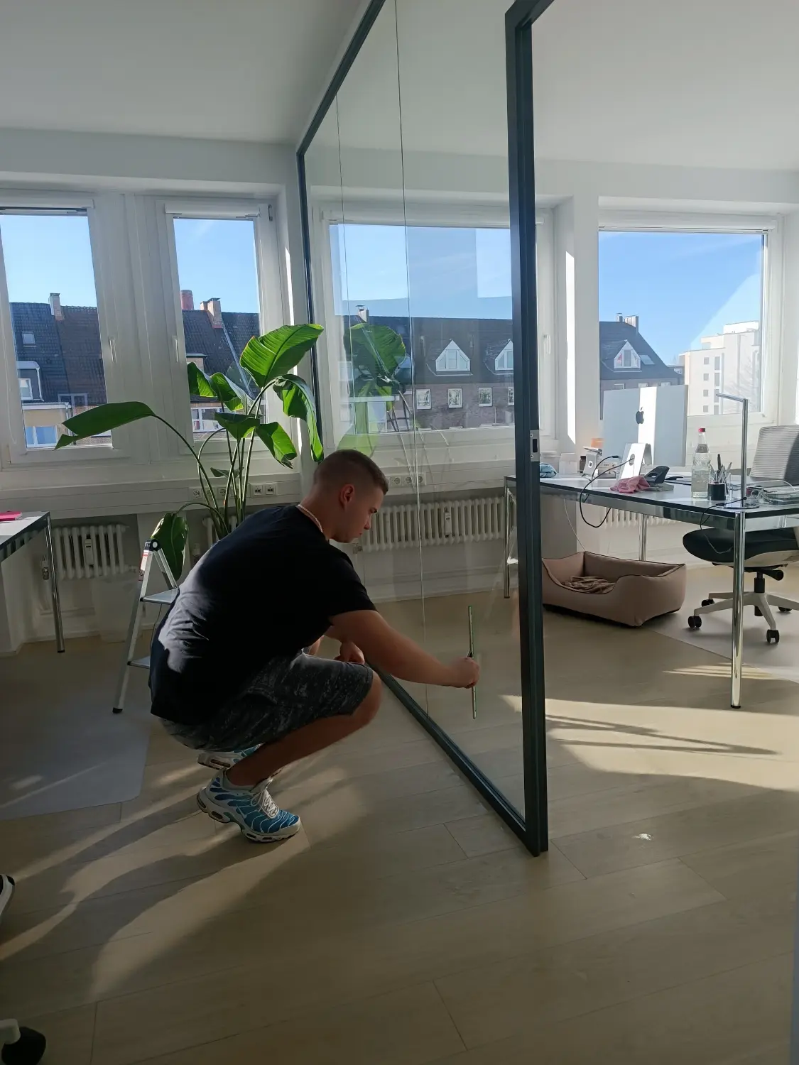 Mann reinigt Glastür von Sunshine Gebäudereinigung